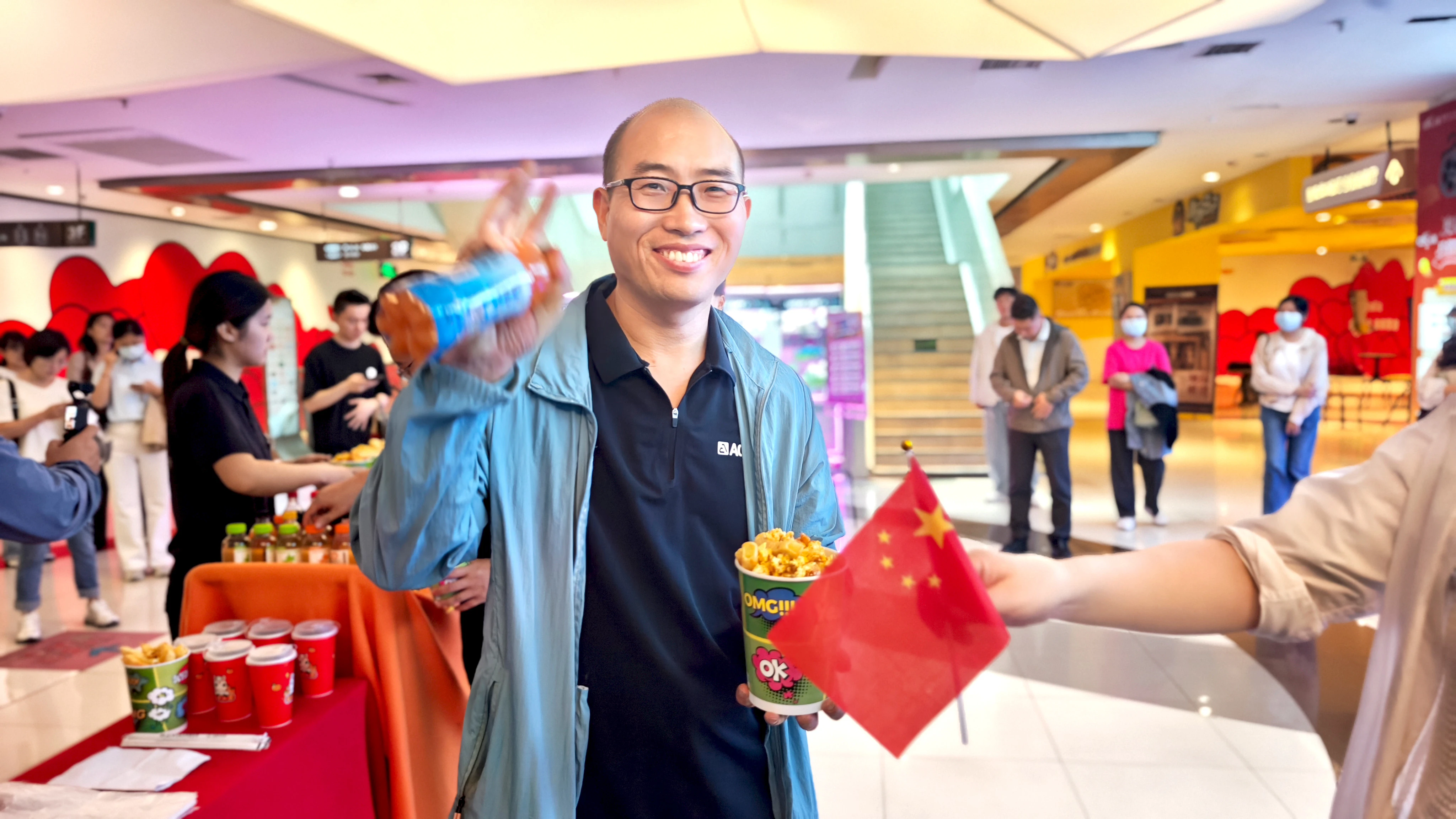 亚建科技员工到达影院，手持小红旗与爆米花准备入场。